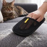 Cat watching as PawGroom furniture mitt removes pet hair from grey sofa