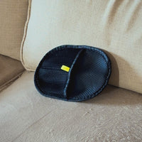 PawGroom furniture mitt on a beige sofa — mesh side with yellow tab