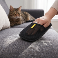 Cat watching as PawGroom furniture mitt removes pet hair from grey sofa